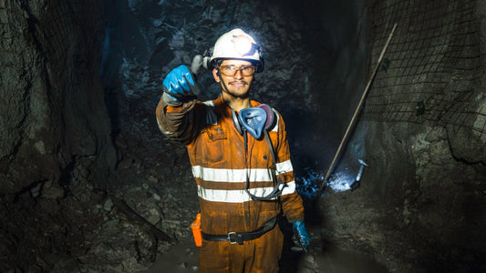 Mineur portant un casque de sécurité et un gilet de protection dans un tunnel de mine, le pouce levé, symbolisant la sécurité et la garantie Mines Raisonnées.